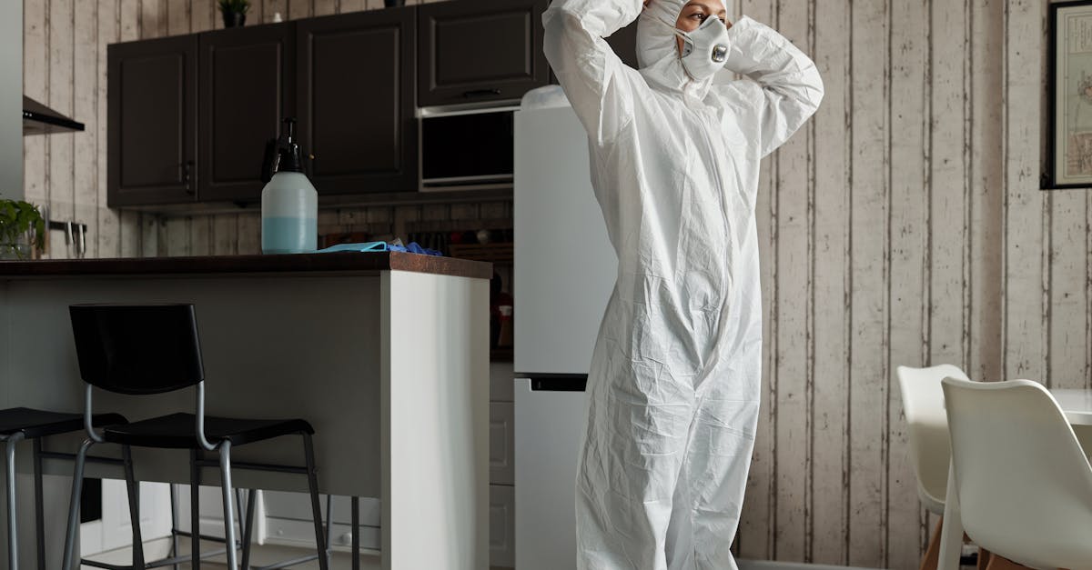 Individual in protective gear standing in a contemporary kitchen setting during the day.