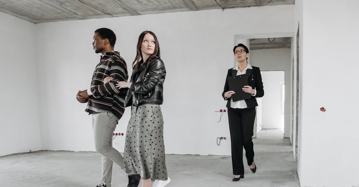 A real estate agent guides potential buyers through a modern home's unfinished interior.